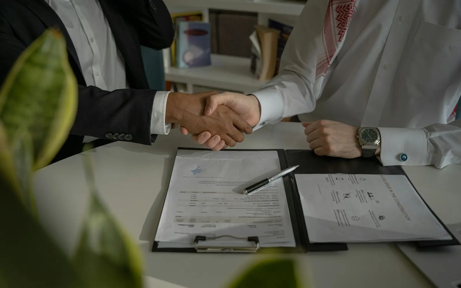 Two people shaking hands over a signed document